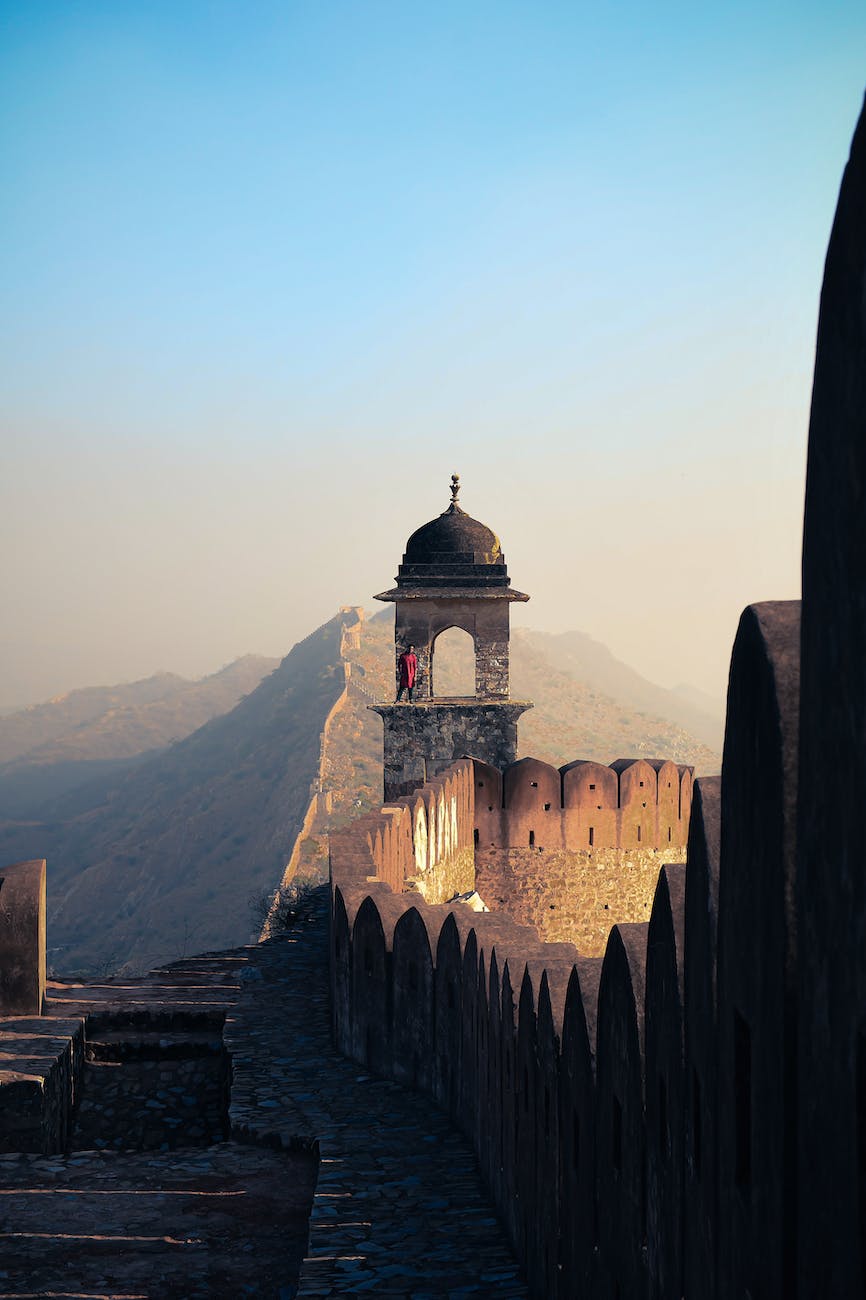old stone fortress near stairs and mountains under blue sky