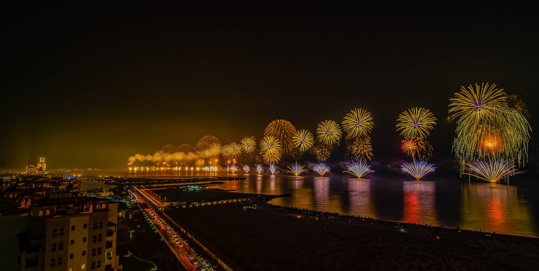 colorful fireworks display at sea along a city